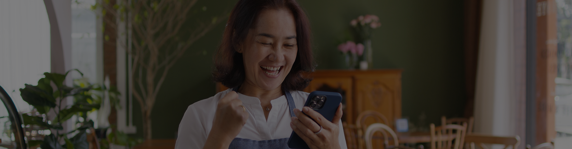 Woman excited looking at her phone, surrounded by tables